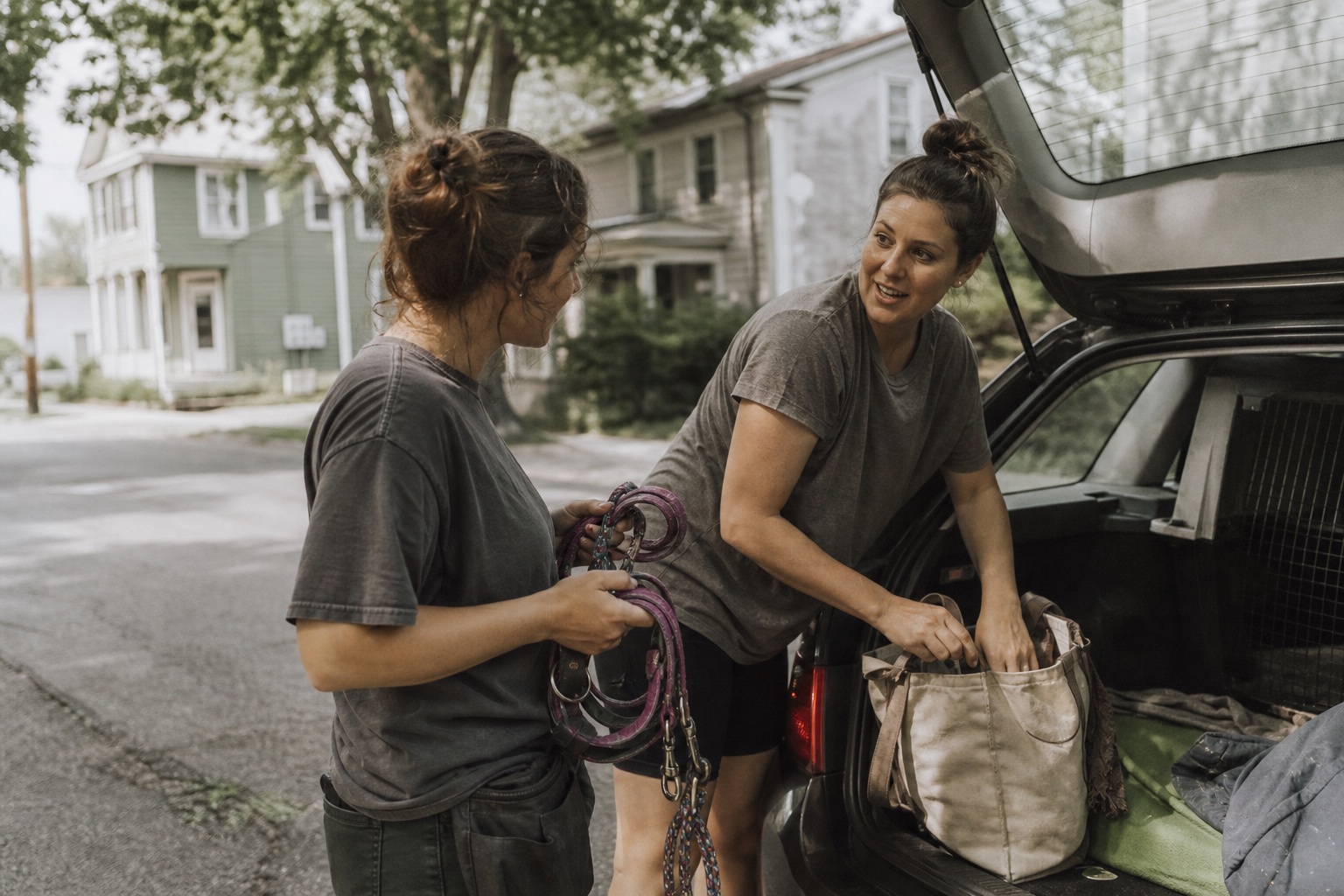 Two Pawside caregivers loading leashes into a car on a quiet residential street